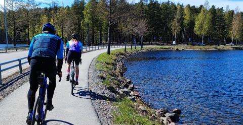 Two cyclist on the road beside blue Lake Saimaa