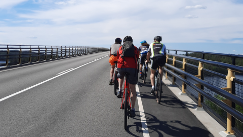 Neljä pyöräilijää ajaa sillalla.
