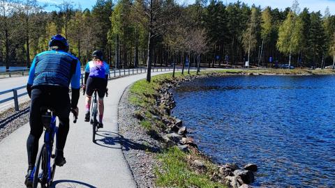 Two cyclist on the road beside blue Lake Saimaa